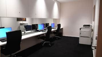 A conference room with multiple desks, computers, and chairs.