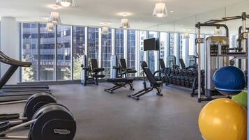 Un gimnasio moderno con equipamiento cardiovascular, máquinas de pesas y pelotas de ejercicio.
