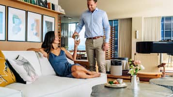 Un salon moderne avec un canapé blanc, une table basse ronde ornée d’un vase de fleurs, et un coin repas à l’arrière-plan.