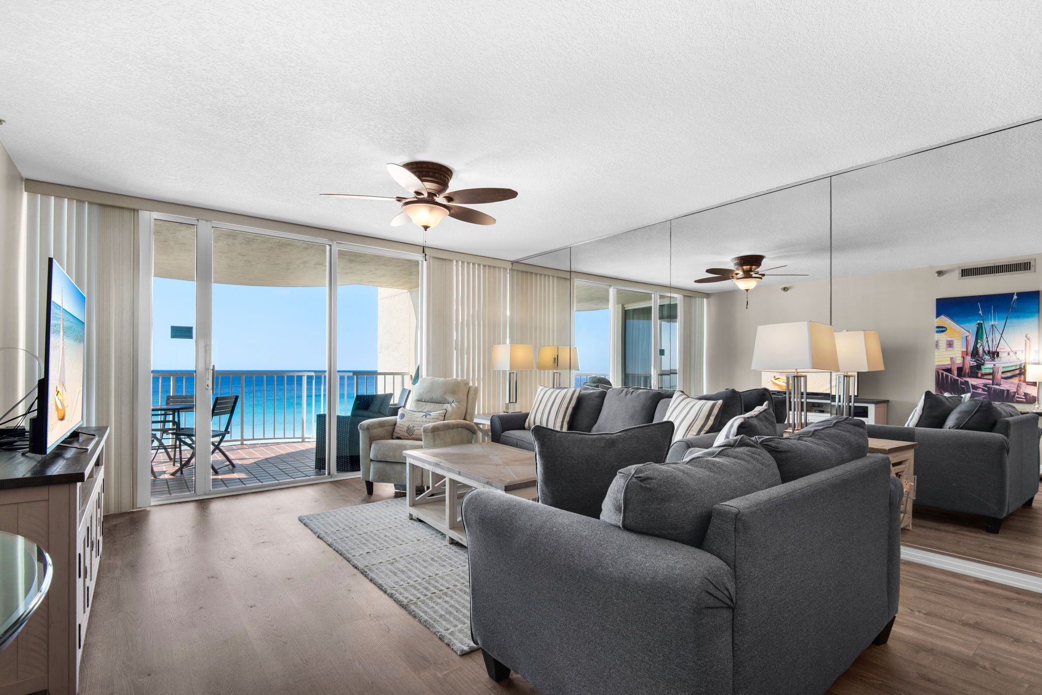 A spacious living room with a balcony, ceiling fans, and a large window with a view.