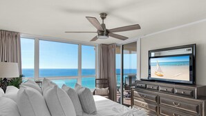 A hotel room with a large bed, a ceiling fan, a TV, and a view of the ocean. - Beach Front, Renovated Kitchen, Free Beach Chair Service (Miramar Beach)