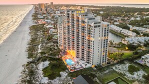 A high-rise hotel with multiple balconies, a swimming pool, and a beach view. - Beach Front, Renovated Kitchen, Free Beach Chair Service (Miramar Beach)