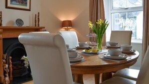 Une salle à manger avec une table ronde dressée pour quatre personnes, une cheminée et une vue sur la ville grâce à de grandes fenêtres.