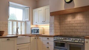 Une cuisine avec des meubles blancs, un four à micro-ondes, un four double et un plan de travail en bois.