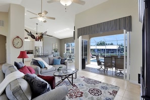 Relax in a spacious living room with a ceiling fan, large window, and comfortable seating area.