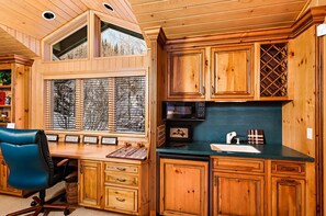L’intérieur d’une cabane en bois comprend un bureau, une chaise et un coin cuisine.