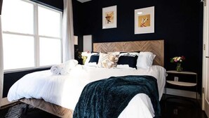Een moderne hotelkamer met een groot bed, een houten hoofdbord en kunstwerken aan de wanden.