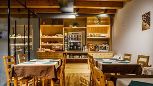 A cozy restaurant with wooden furniture, a central counter with a coffee machine, and shelves stocked with snacks and beverages. - Posada Rural Fuente Juliana (Ruente)