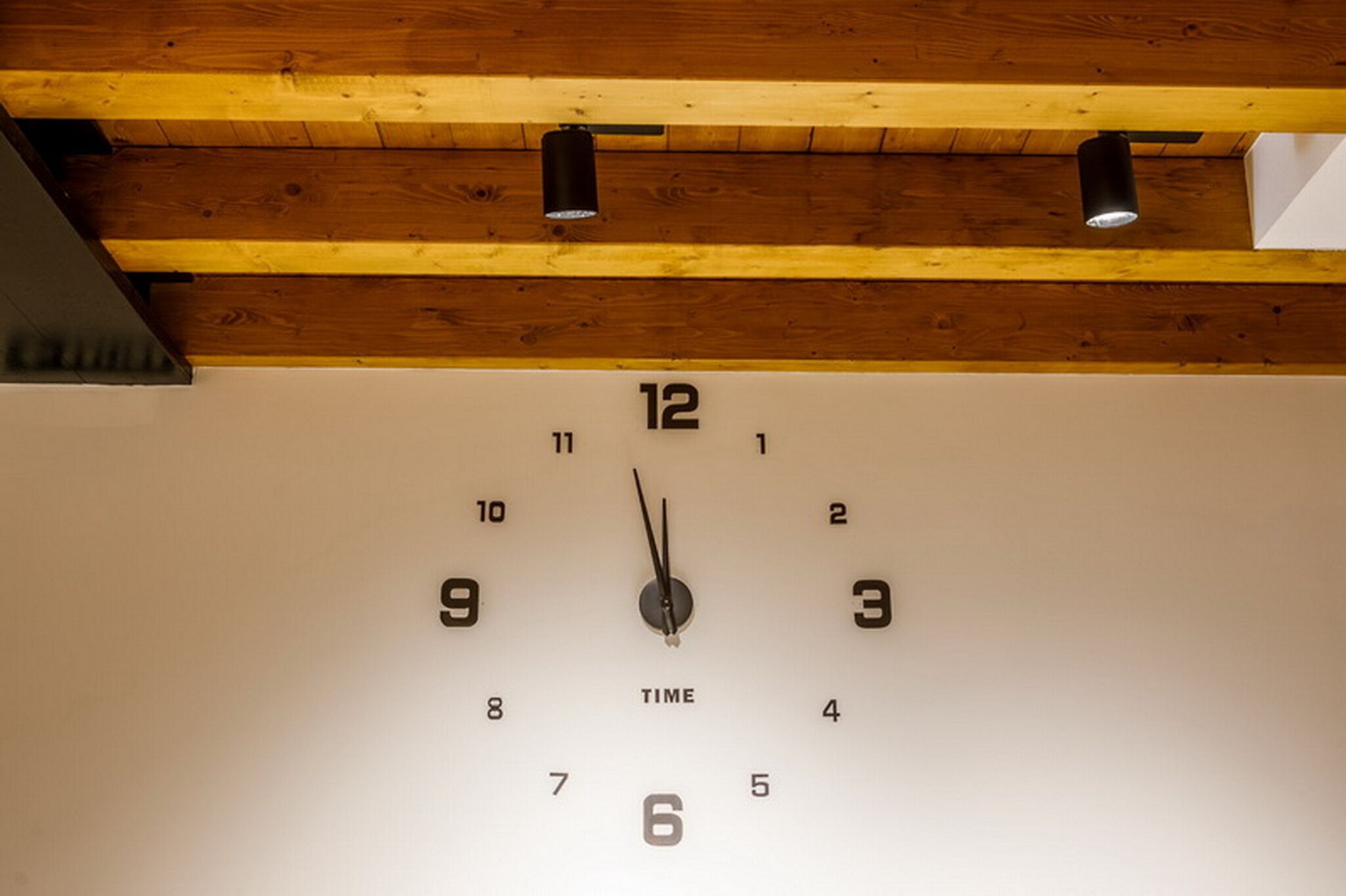 A wall clock with a wooden ceiling above.