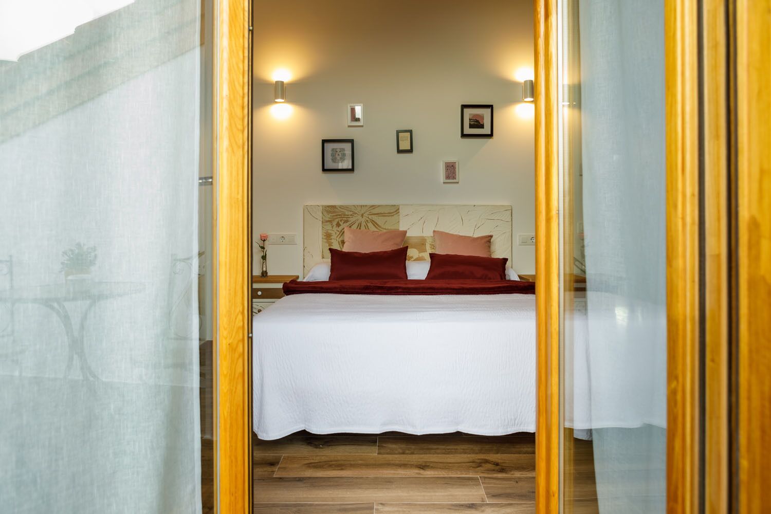 A bedroom with a bed, a nightstand, and wall-mounted lights.