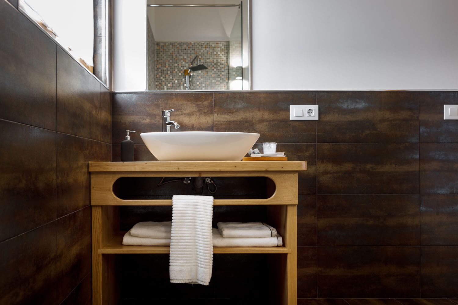 Un baño con un lavamanos de pedestal grande, tocador de madera y un espejo encima.