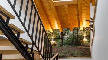 Un escalier en bois avec des rampes noires menant à une pièce dotée d’une lucarne.