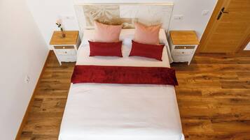 Un dormitorio ordenado con una cama, dos mesitas de noche y un armario de madera.