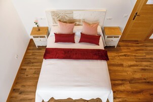 Quarto bem arrumado com uma cama, duas mesas de cabeceira e um guarda-roupa de madeira.