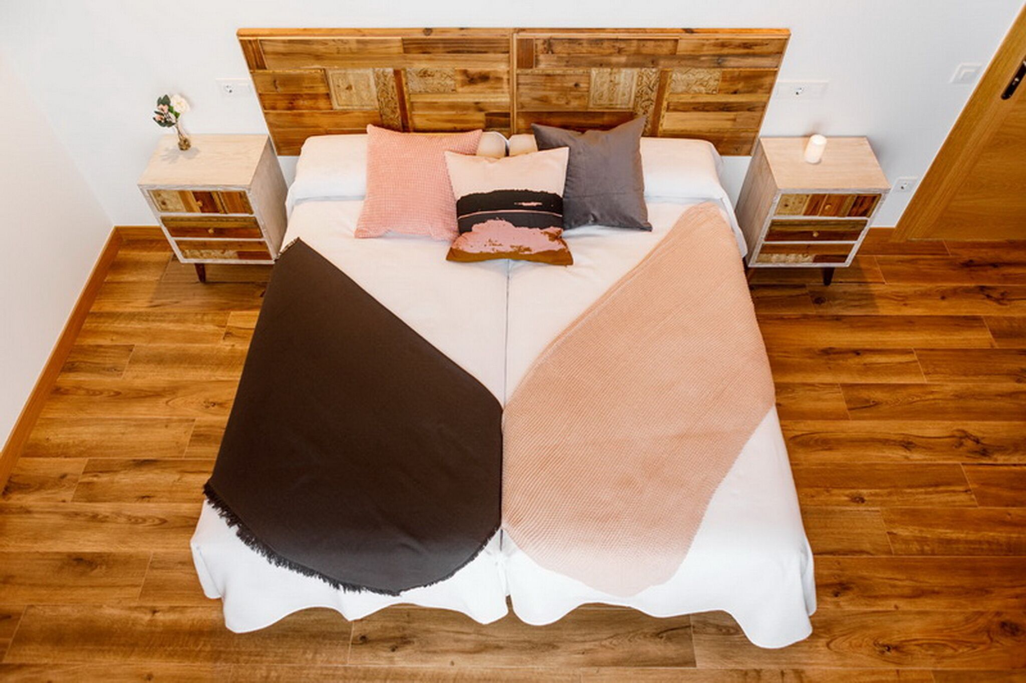 A double bed with a wooden headboard, two bedside tables, and a wooden floor.