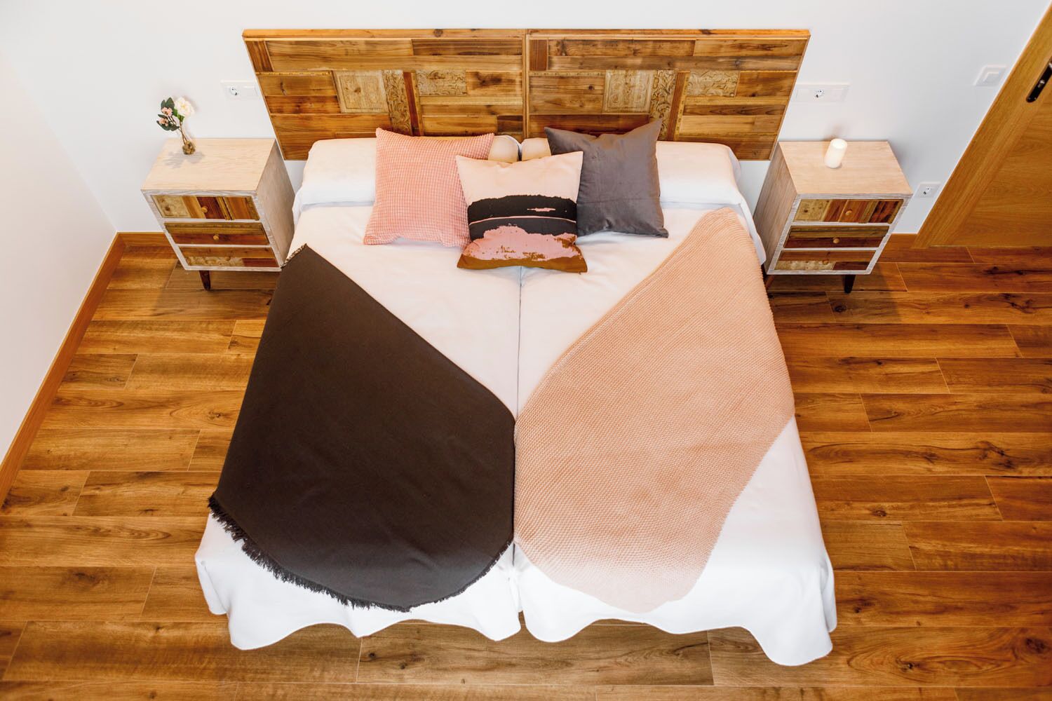 Un lit avec une tête de lit en bois, deux tables de chevet et un plancher en bois.