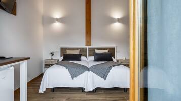 A double bed with a wooden headboard, two bedside tables, and a small nightstand with a lamp.