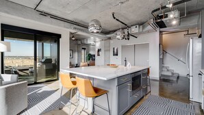 A modern kitchen with a large island, bar stools, and a view through a glass door. - MINNeSTAY* Sable 701 - Luxury Two Story Loft | North Loop | Target Center (Minneapolis)
