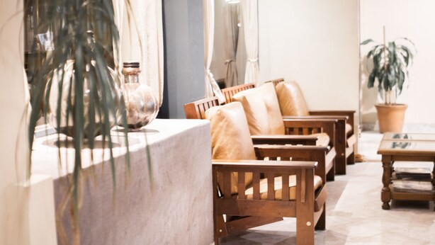 A seating area with wooden chairs and a table, a potted plant, and a vase on a counter. - Once Plaza Hotel (Buenos Aires)