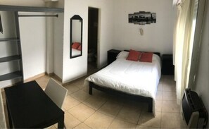 A bedroom with a bed, a desk, a chair, a mirror, and a wall-mounted artwork. - Once Plaza Hotel (Buenos Aires)