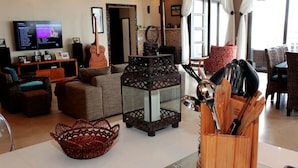 Un salon chaleureux avec une télévision, une guitare, une lanterne décorative et un panier.