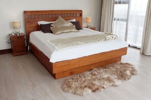 Een slaapkamer met een houten bed, twee nachtkastjes met lampen, een zacht tapijt en een raam met gordijnen.
