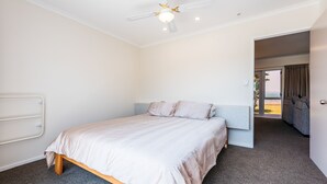 Een slaapkamer met een bed, een plafondventilator en uitzicht door een open deur op een balkon.