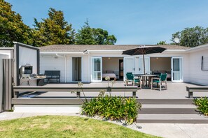A modern mobile home with a patio area featuring a dining table, chairs, and an umbrella. - Number Six - Oneroa Holiday Home (Oneroa)