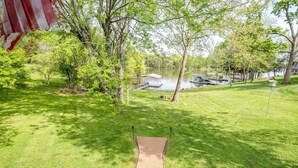 A grassy yard with a concrete path leading to a dock over a lake, surrounded by trees and a small building. - Lakefront | Sauna | Kayaks | Firepit | 35 Min to Nashville (Gallatin)