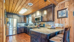 A modern kitchen with wooden cabinets, stainless steel appliances, and a granite countertop. - Lakefront | Sauna | Kayaks | Firepit | 35 Min to Nashville (Gallatin)