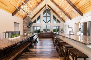 A spacious kitchen with a long island, wooden beams, stone accents, and large windows. - Lake Views, Indoor/Outdoor Pool, Hot Tub, sleeps34 (Branson)