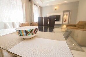 A modern living room with a dining table, a colorful bowl, and a sofa.