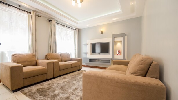 Un salón moderno con sofás color beige, un televisor de pantalla plana y una chimenea.