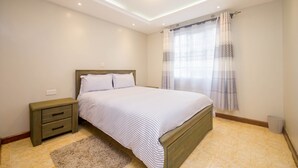Un dormitorio con cama, mesita de noche y ventana con cortinas.