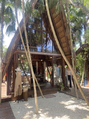 Un hotel de disseny amb teulada de palla, bigues de fusta i palmeres.