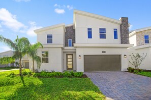 A modern two-story house with a garage, a well-maintained lawn, and a brick driveway.