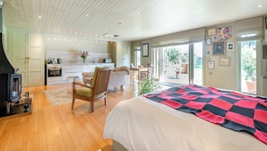 Un dormitorio moderno con una cama grande, suelo de madera, kitchenette y vistas al exterior.