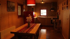 Un intérieur en bois comprenant une table à manger, un réfrigérateur rouge, une fenêtre et un coin cuisine.