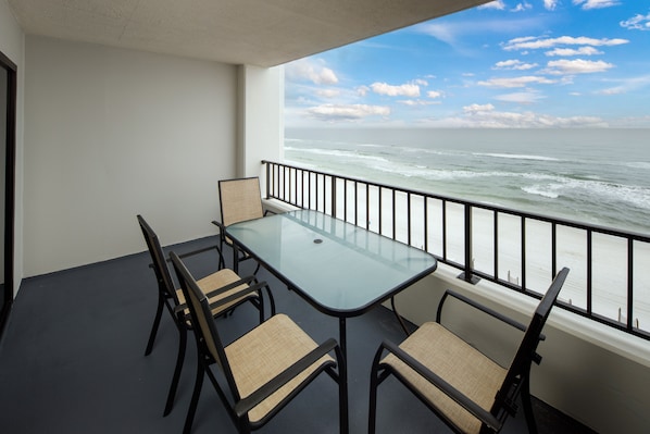 A balcony with a glass table and chairs, overlooking the ocean. - Surf Dweller 709 - Tidal Treasures (Fort Walton Beach)