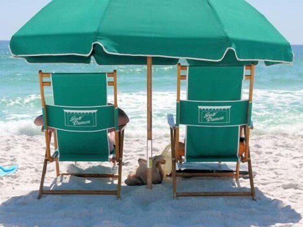 Two beach chairs with green umbrellas labeled "Golf Dreams" on a sandy beach with the ocean in the background. - Gulf Dunes 608 - Seas the Gulf (Fort Walton Beach)