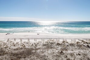 Una playa con arena, una valla y el océano al fondo.