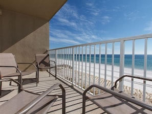 A balcony with a view of the beach, equipped with lounge chairs and a railing. - Emerald Twrs West 3003 by Brooks and Shorey Resorts (Fort Walton Beach)