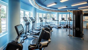 Una palestra con macchinari cardio, attrezzature per l'allenamento con i pesi e ampie finestre.