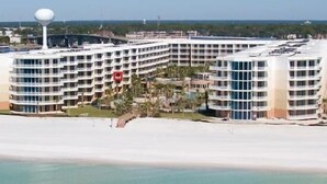 A large, multi-story hotel with a curved facade, located adjacent to a beach. - Waterscape B310 - Resort Shores (Fort Walton Beach)