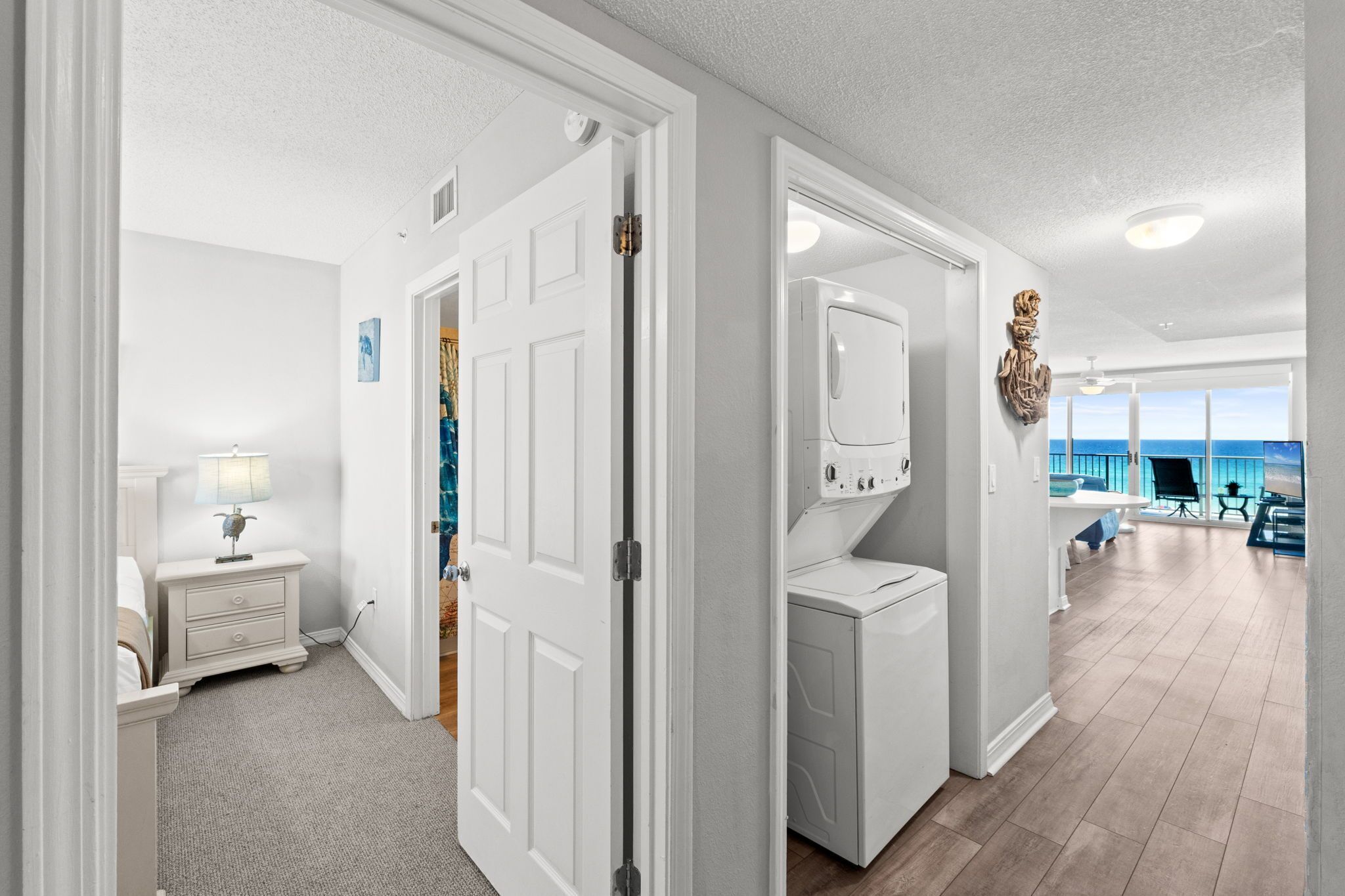 A hallway with a door leading to a laundry area and a view of the ocean.