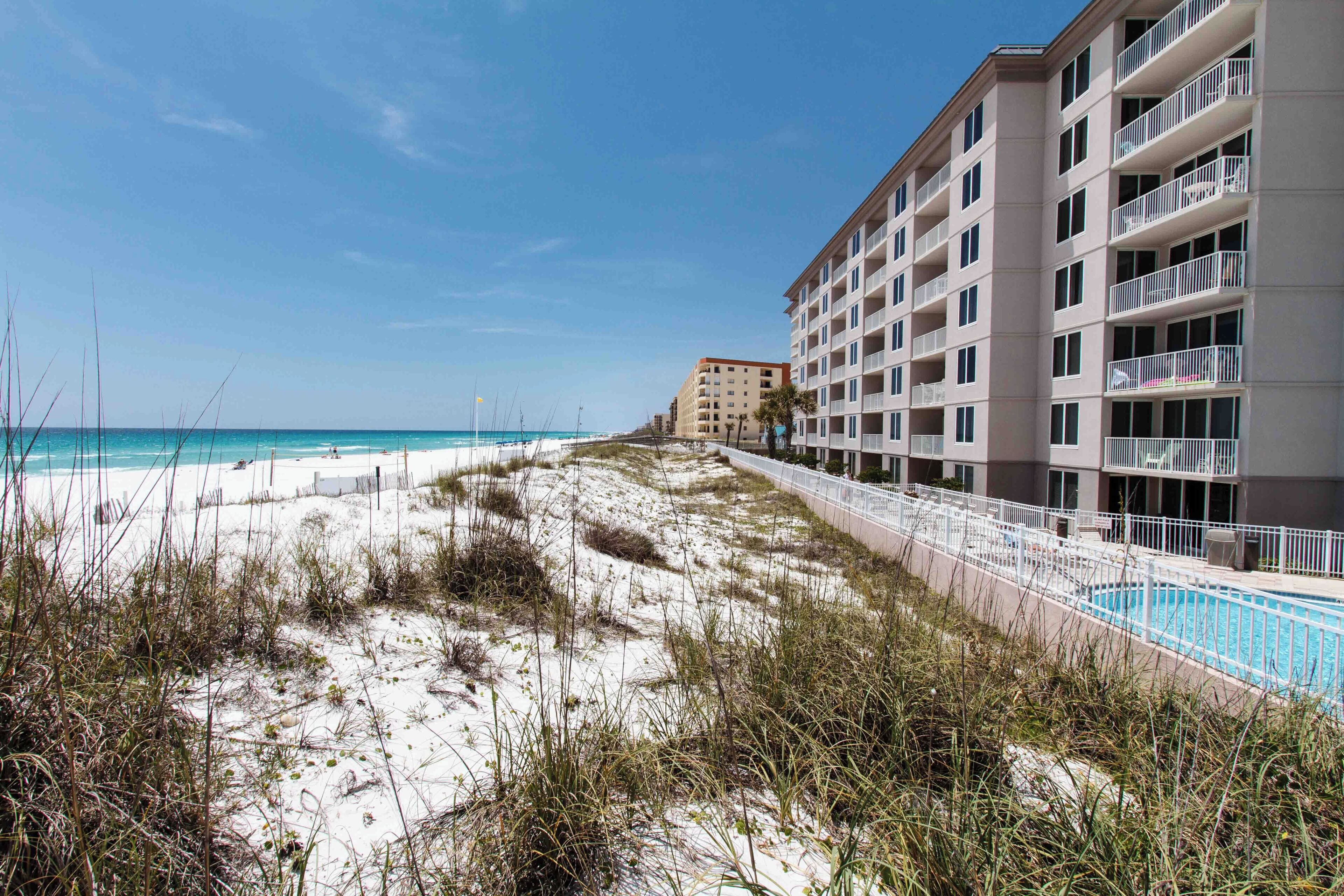 A beachfront hotel with a swimming pool and a sandy beach.
