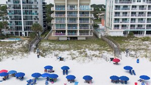 A beachfront hotel with multiple balconies, a pool, and beach umbrellas. - Gulfside 302 - Ocean Serenity (Fort Walton Beach)