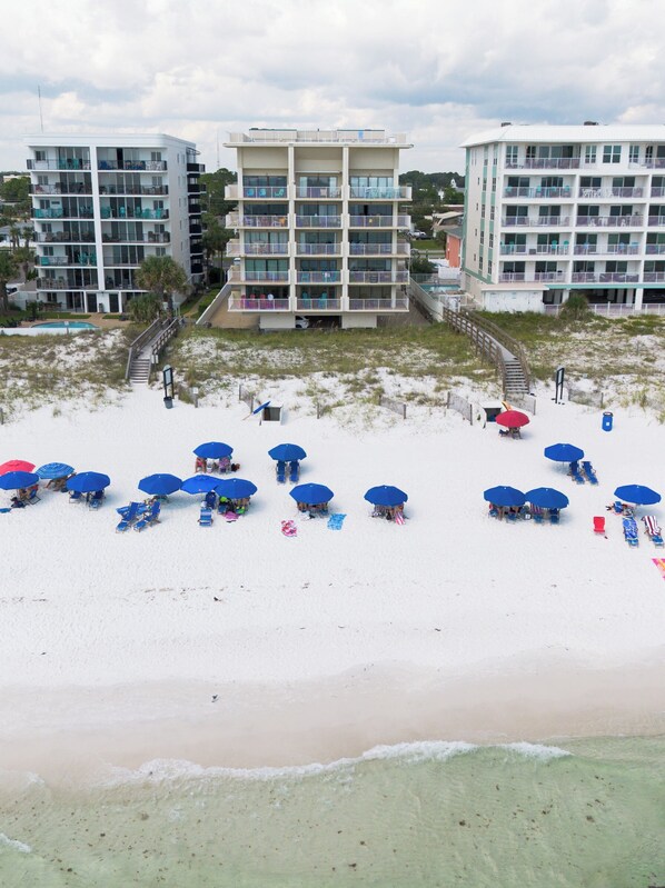 Un hôtel situé en bord de mer, doté de nombreux balcons, d’une piscine et de parasols de plage.
