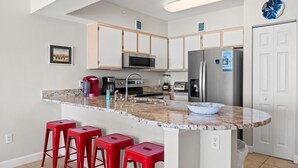 Eine moderne Küche mit Granit-Arbeitsplatten, Edelstahlgeräten und roten Barhocker.