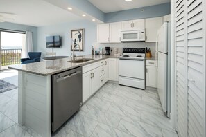 A modern kitchen with white cabinets, a built-in microwave, a dishwasher, and a stove. - Emerald Towers West 1003 - Sandy Toes (Fort Walton Beach)